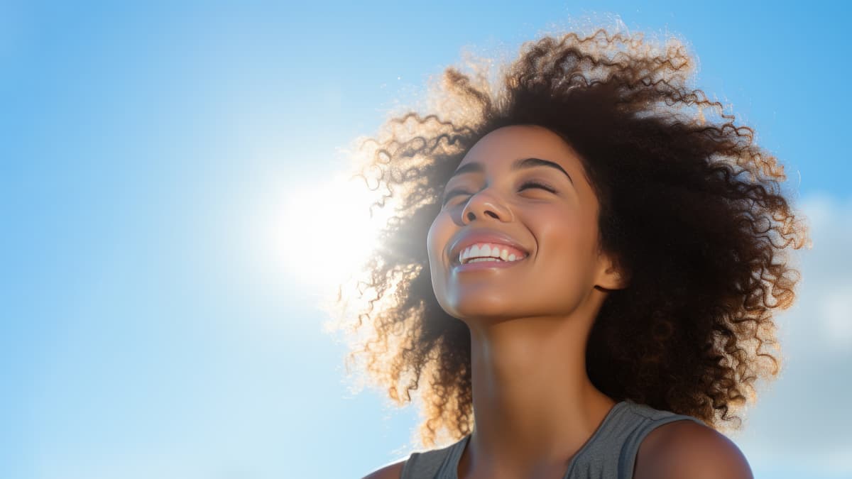 African woman breathes calmly looking up on clear blue sky