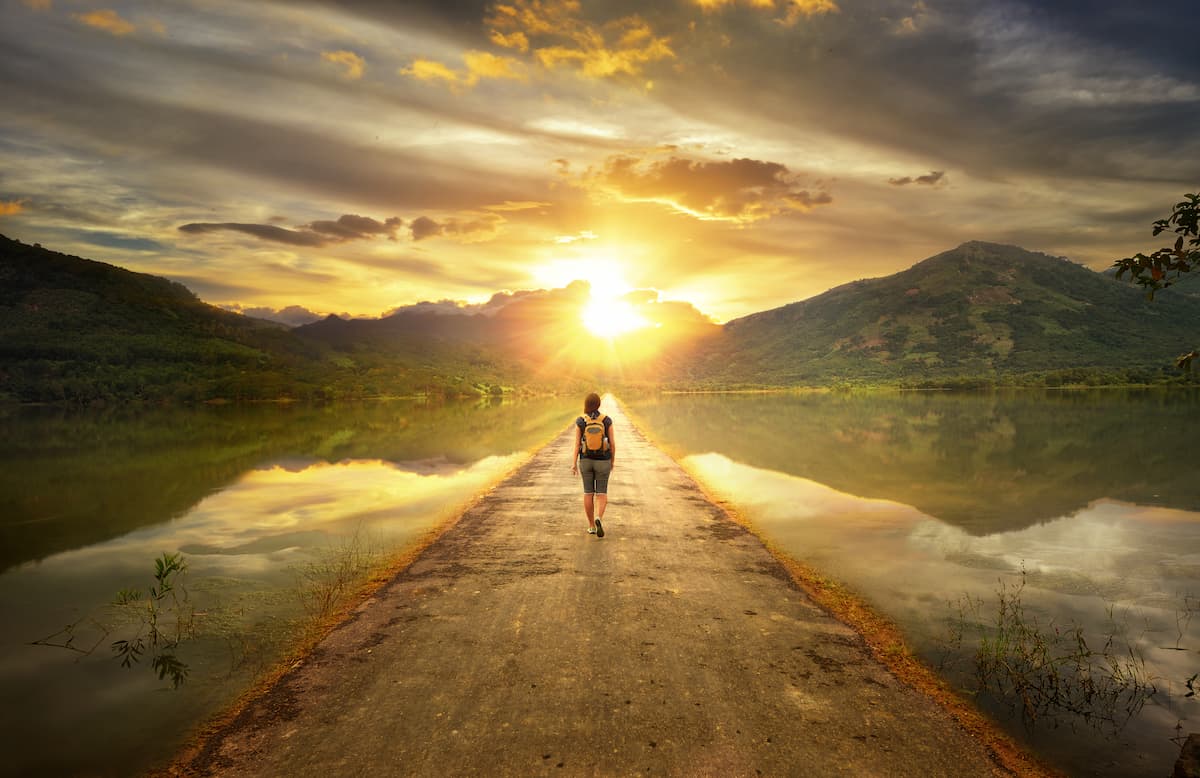 person walking on a path towards the mountains